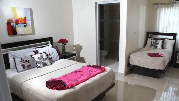 Une chambre d’hôtel avec un grand lit, un lit plus petit et une salle de bain.