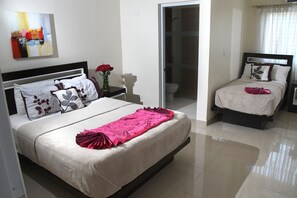 A hotel room with a large bed, a smaller bed, and a bathroom. - Hostal San Francisco de Asis (Santo Domingo)