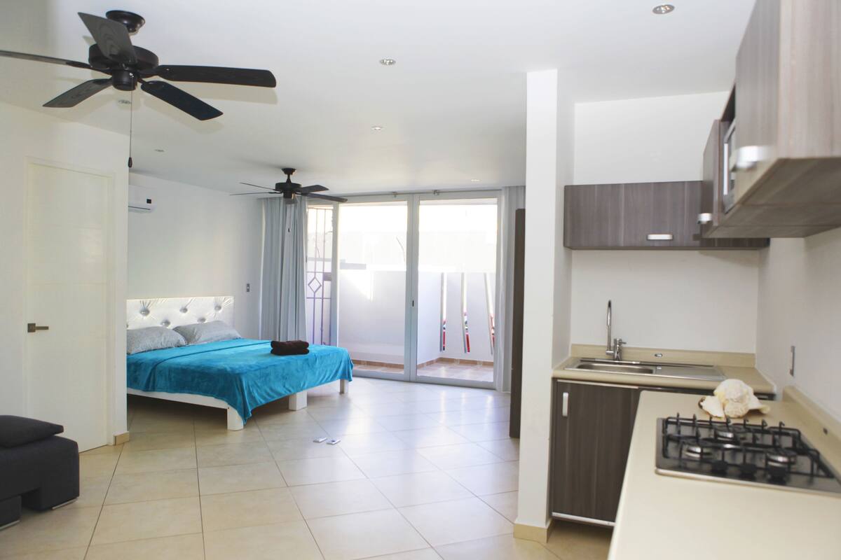 A bedroom with a bed, a ceiling fan, and a view to a balcony.