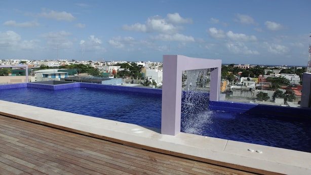 A rooftop pool with a water feature and a view of the cityscape. - IRIS Studios & Apartments (Playa del Carmen)