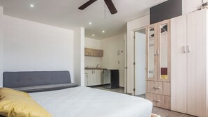 A bedroom with a bed, a wardrobe, and a kitchenette in the background. - IRIS Studios & Apartments (Playa del Carmen)