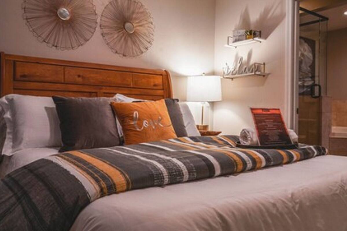 A neatly made bed with striped bedding, a wooden headboard, and decorative wall sconces.