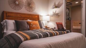 Een net opgemaakt bed met gestreepte lakens, een houten hoofdbord en decoratieve wandlampen.