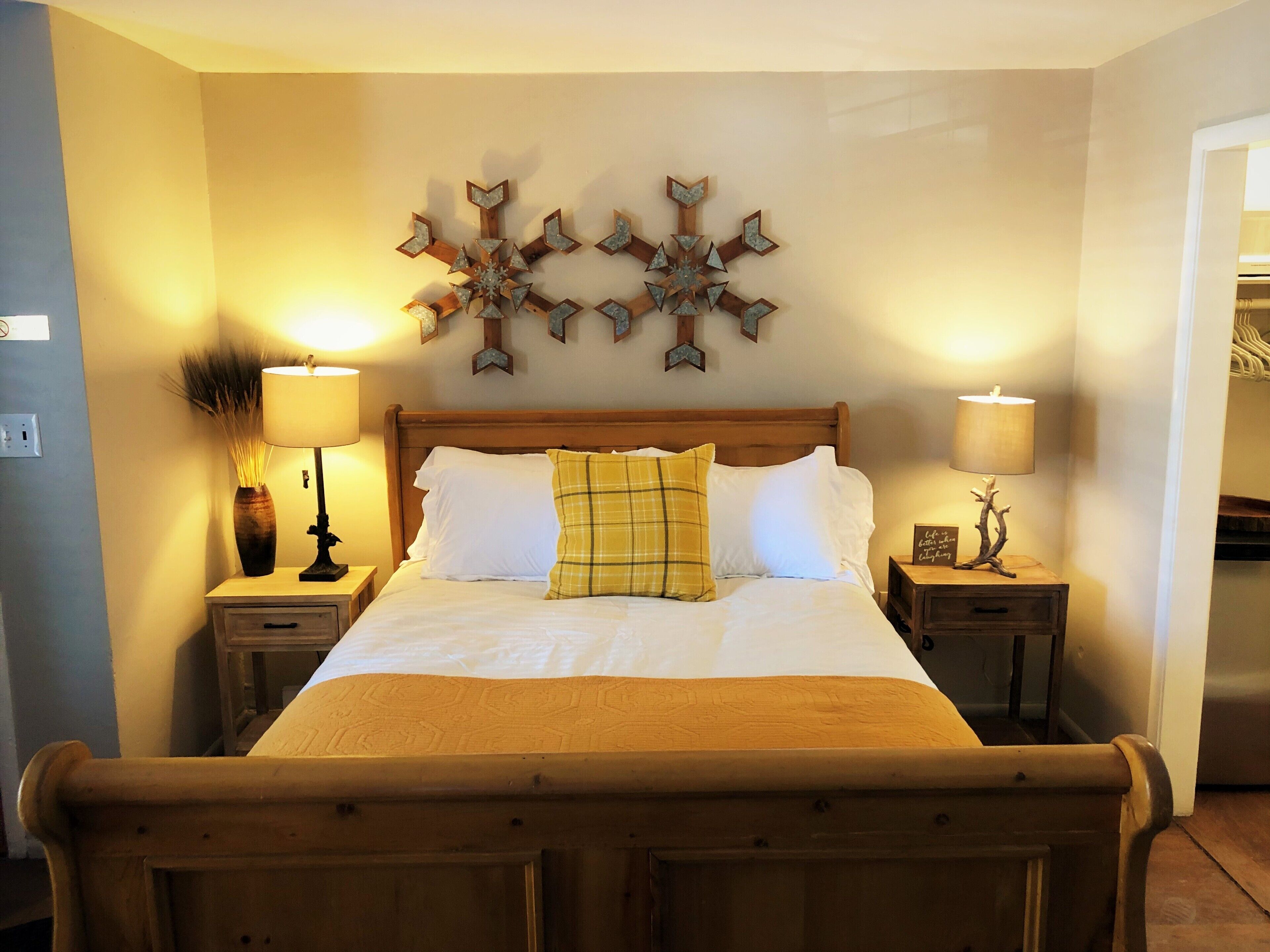 A neatly made bed with a wooden headboard, two bedside tables with lamps, and a wall-mounted star-shaped decoration.