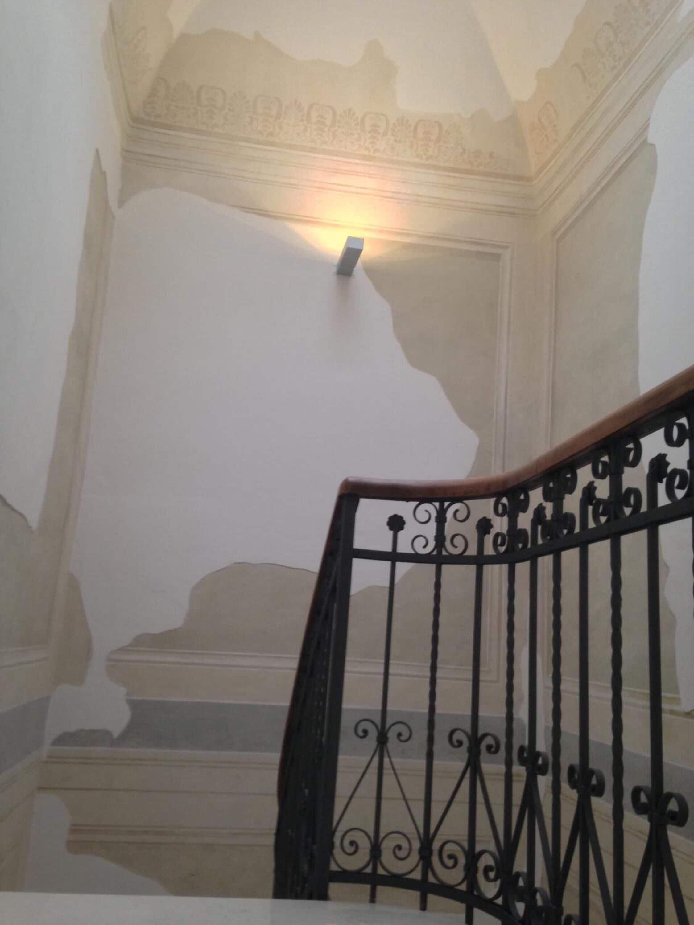 A staircase with ornate black railings and a light fixture above the steps.