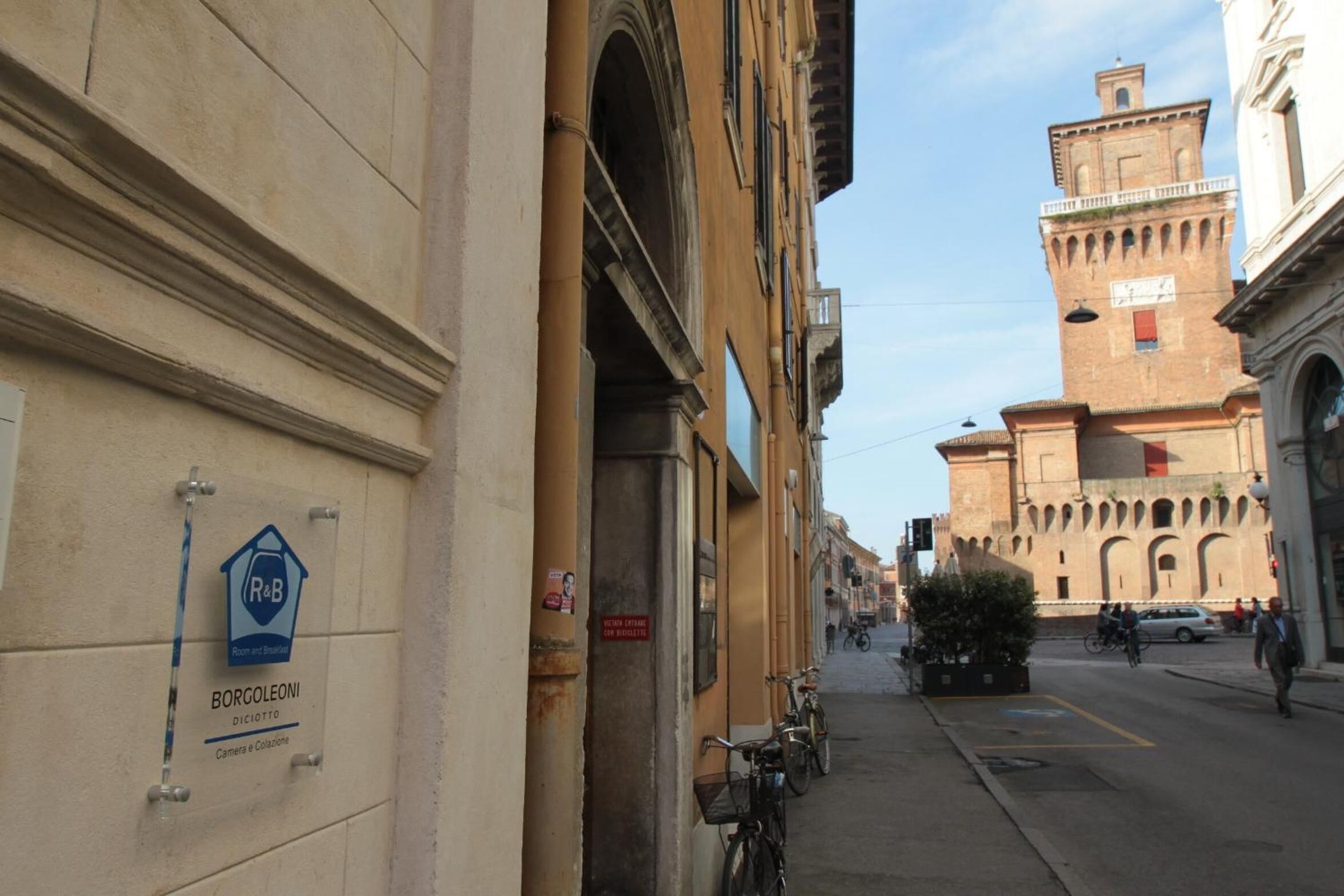 Une vue de rue avec un bâtiment portant l’inscription « BORGOLONI » et une enseigne indiquant « Chambres et suites ».