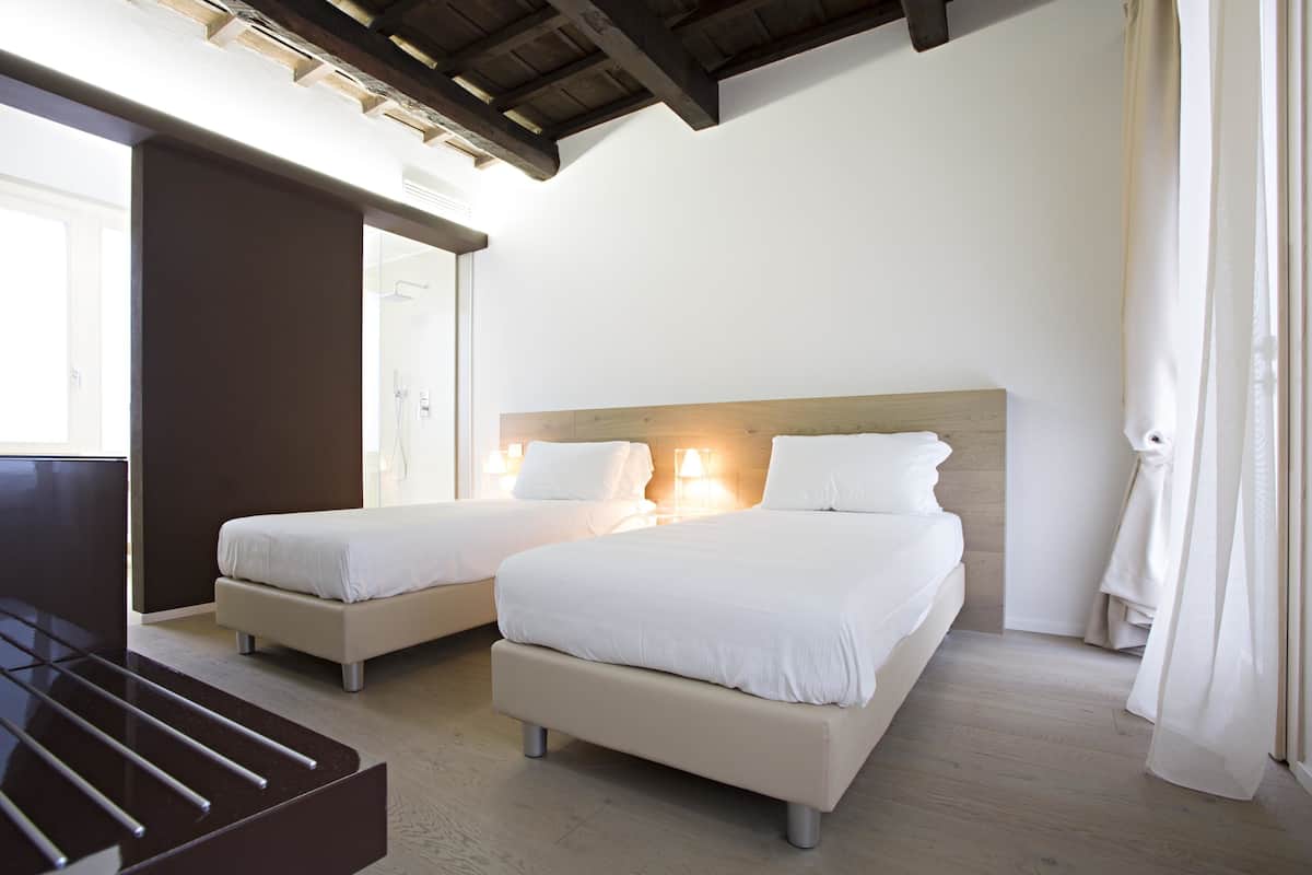 A hotel room with two beds, a wooden headboard, a large mirror, and a wooden floor.