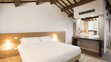 A bedroom with a bed, bedside lamps, a wooden headboard, a desk with a mirror, and a ceiling fan.