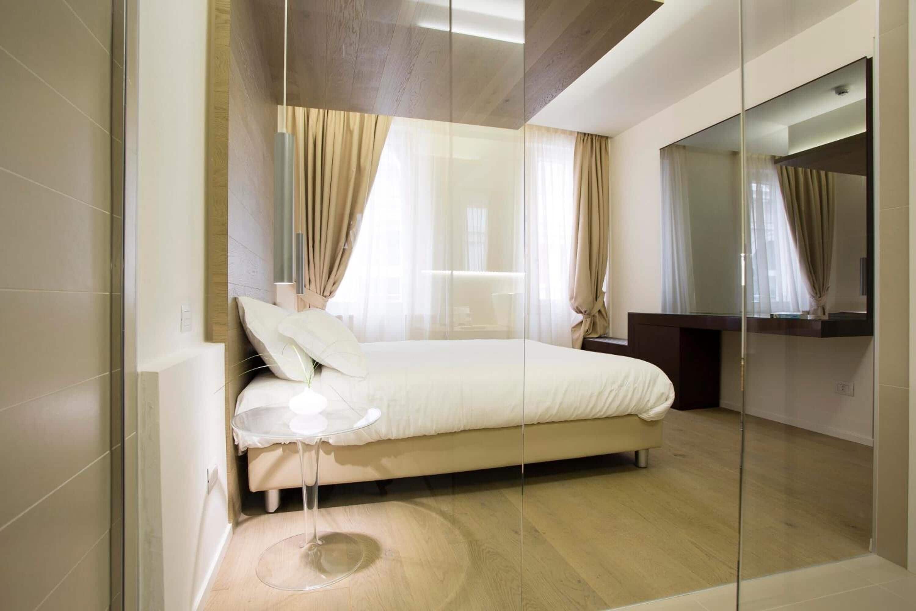 A modern bedroom with a large bed, a glass shower enclosure, and a large mirror.