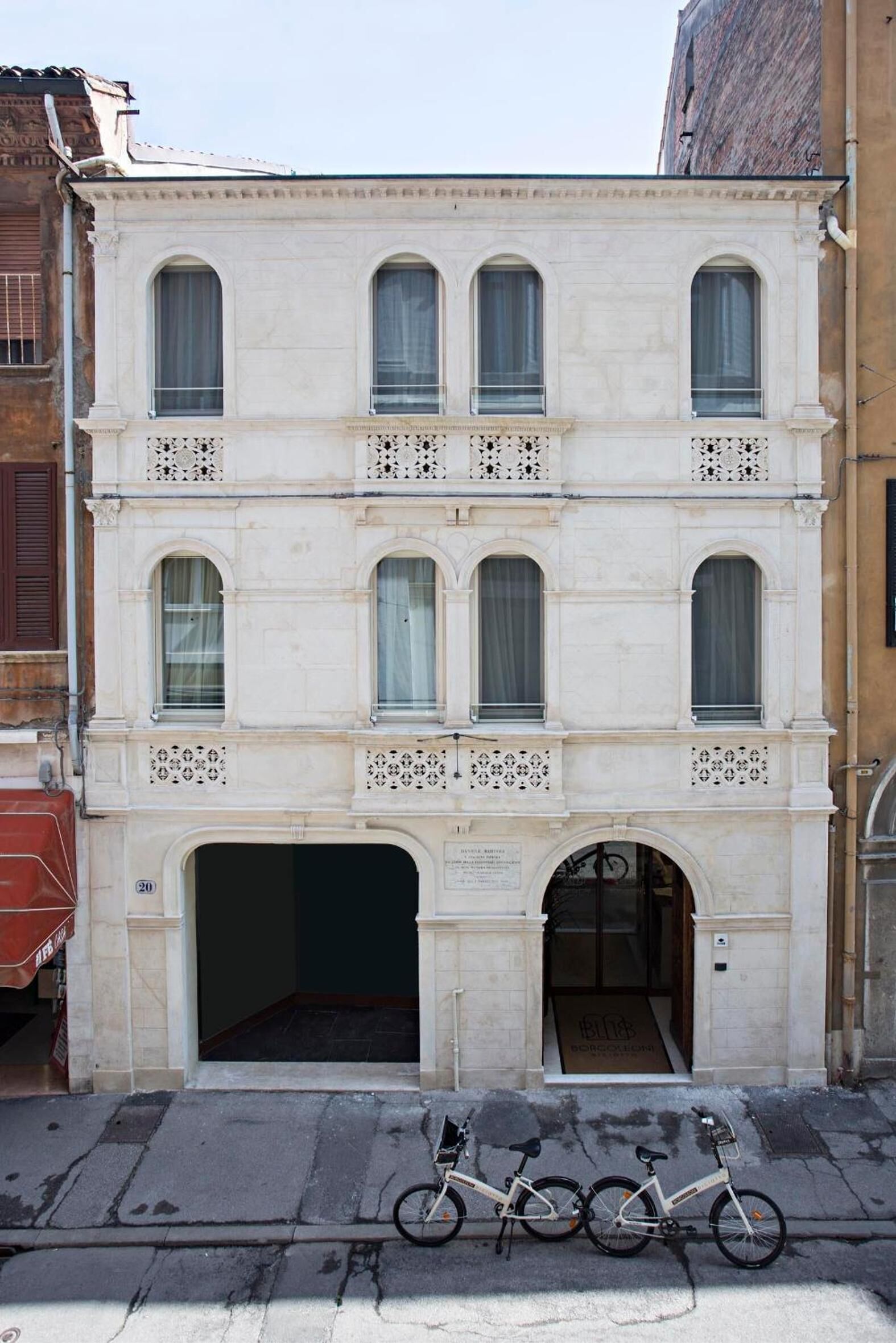 Un bâtiment à deux étages avec une entrée centrale et deux vélos garés devant.
