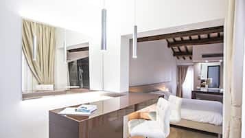 A modern hotel room with a large bed, a desk with a chair, a mirror, and a window with curtains.