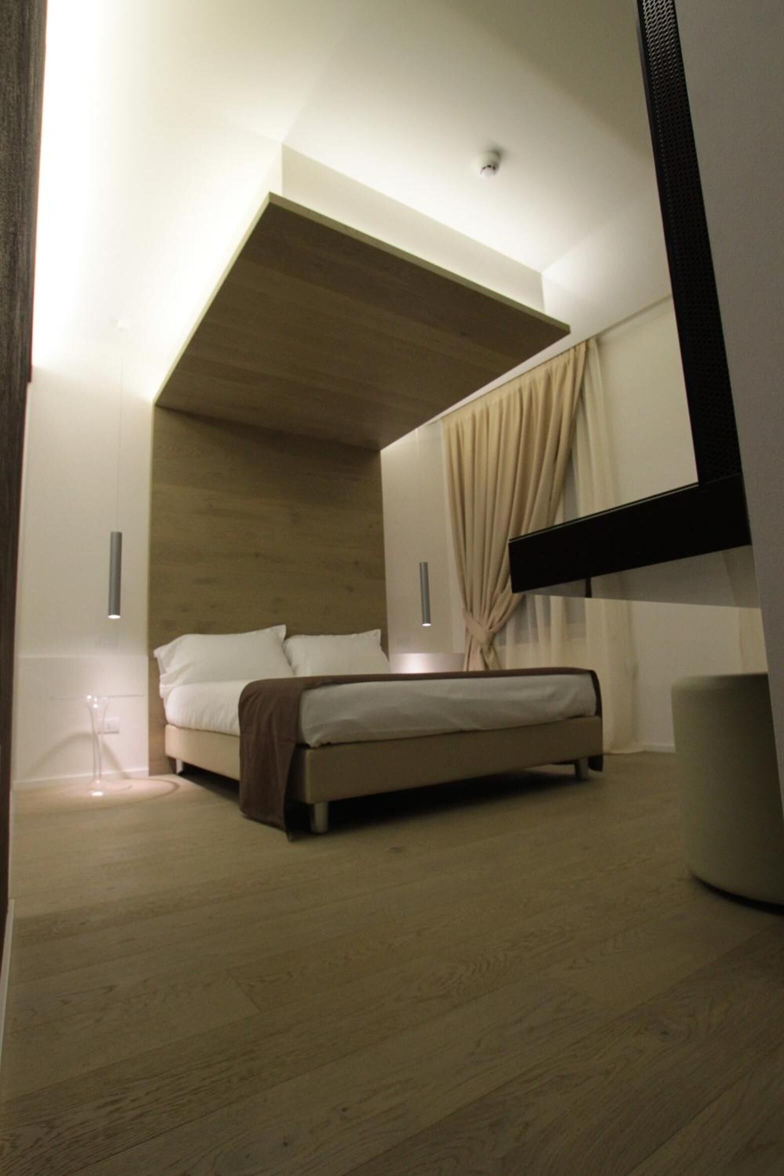 Un dormitorio con cama, techo de madera, un espejo grande y una lámpara.