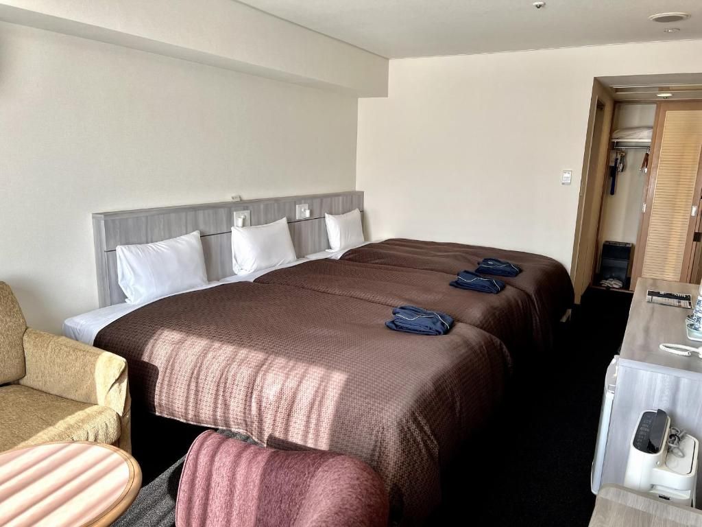 A hotel room with a large bed, a sofa, a desk with a telephone, and a wardrobe.