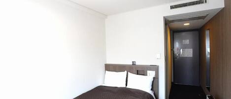 Una habitación de hotel con cama, escritorio y puerta que da a otra habitación.