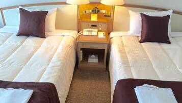 A hotel room with two beds, a nightstand with a lamp, a phone, and a small table.