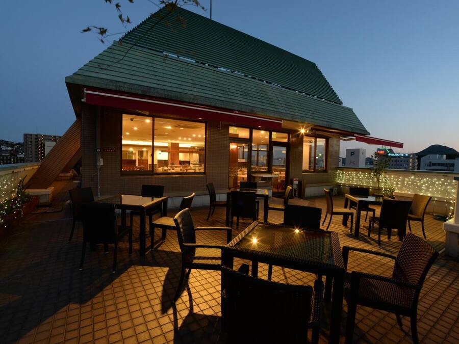 A rooftop restaurant with outdoor seating, a green roof, and string lights.