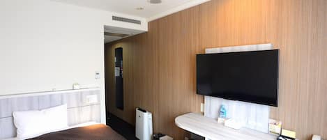 A hotel room with a bed, a desk, a television, and a minibar.