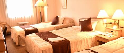 Quarto de hotel com duas camas, uma escrivaninha e uma cadeira.