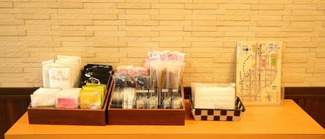 A reception desk with a wooden counter, a brick wall background, and various items including a map, brochures, and a basket.