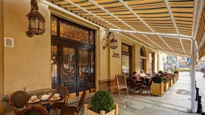 An outdoor café with wooden tables and chairs, a covered seating area, and decorative lanterns.