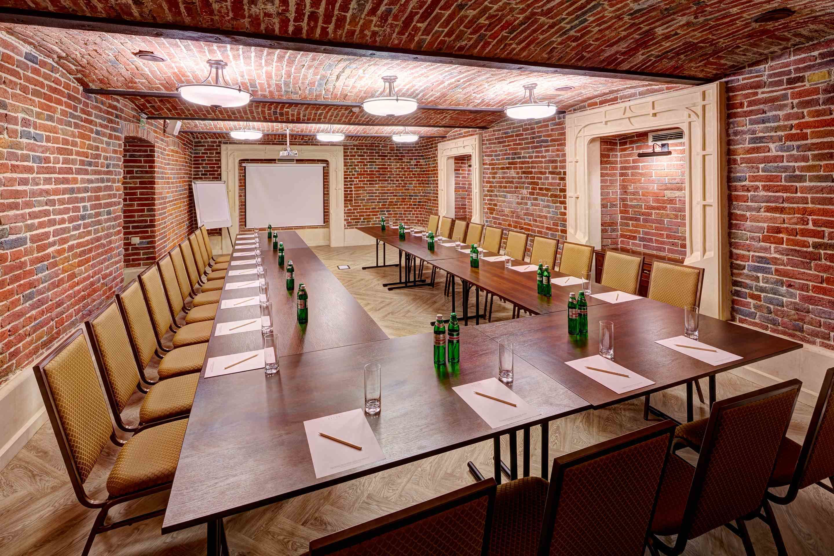 Ein Konferenzraum mit langem Tisch, Stühlen und einer Whiteboard-Wand.