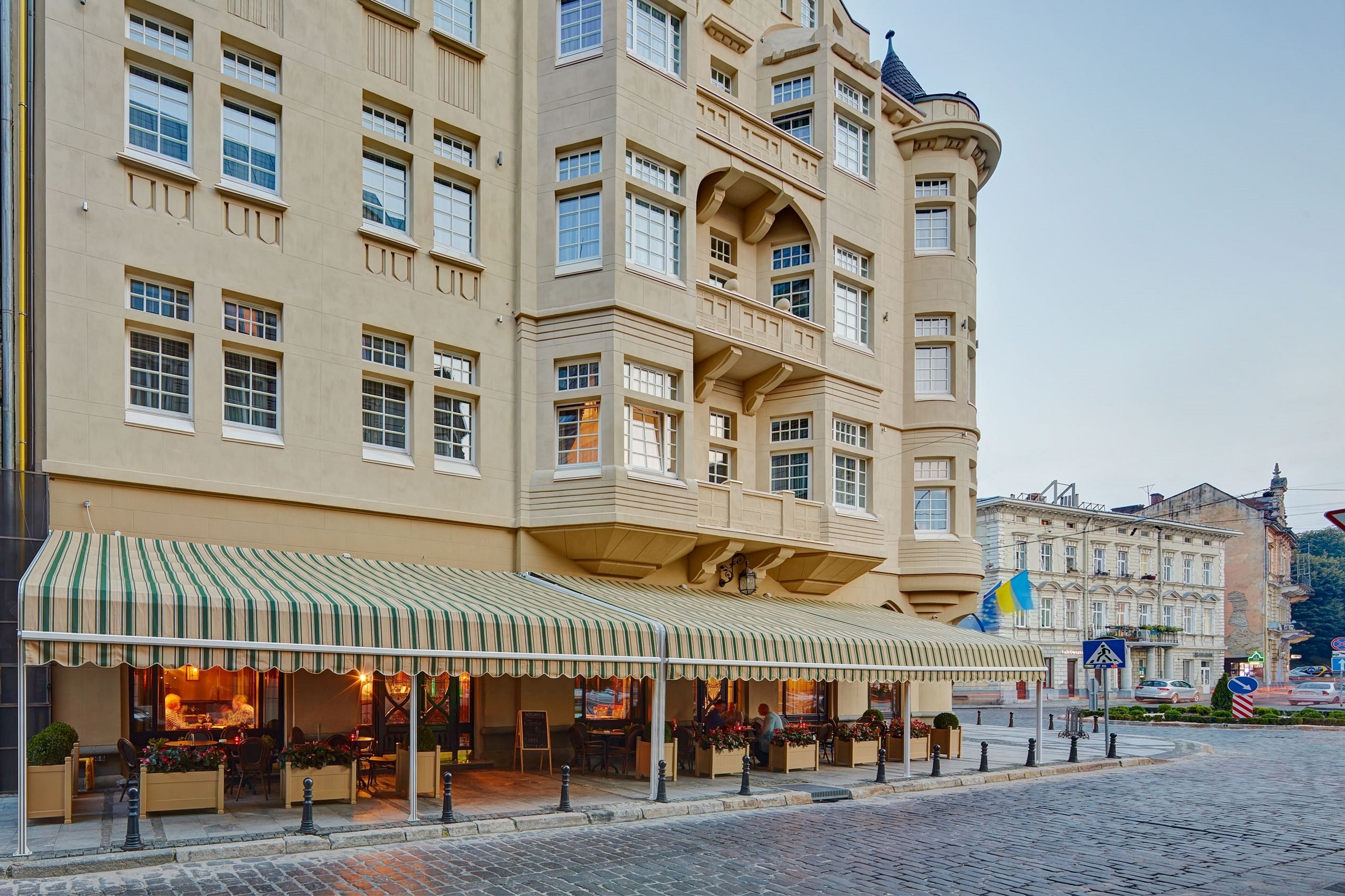 A hotel with a large outdoor seating area, multiple balconies, and a prominent corner tower.