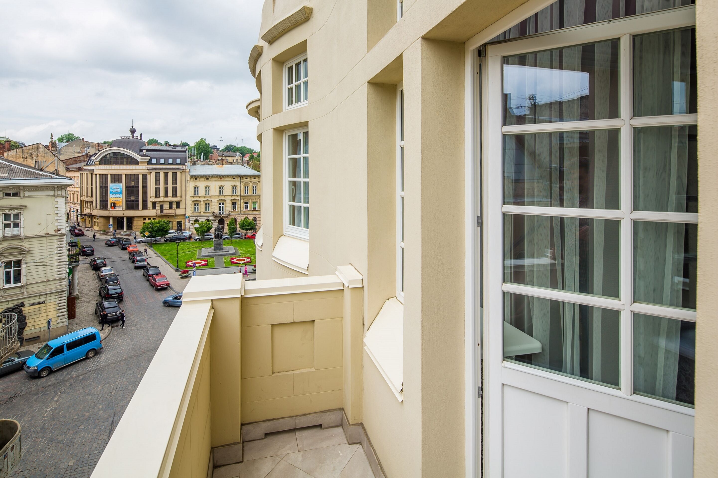 A balcony with a view of a street and parked cars.