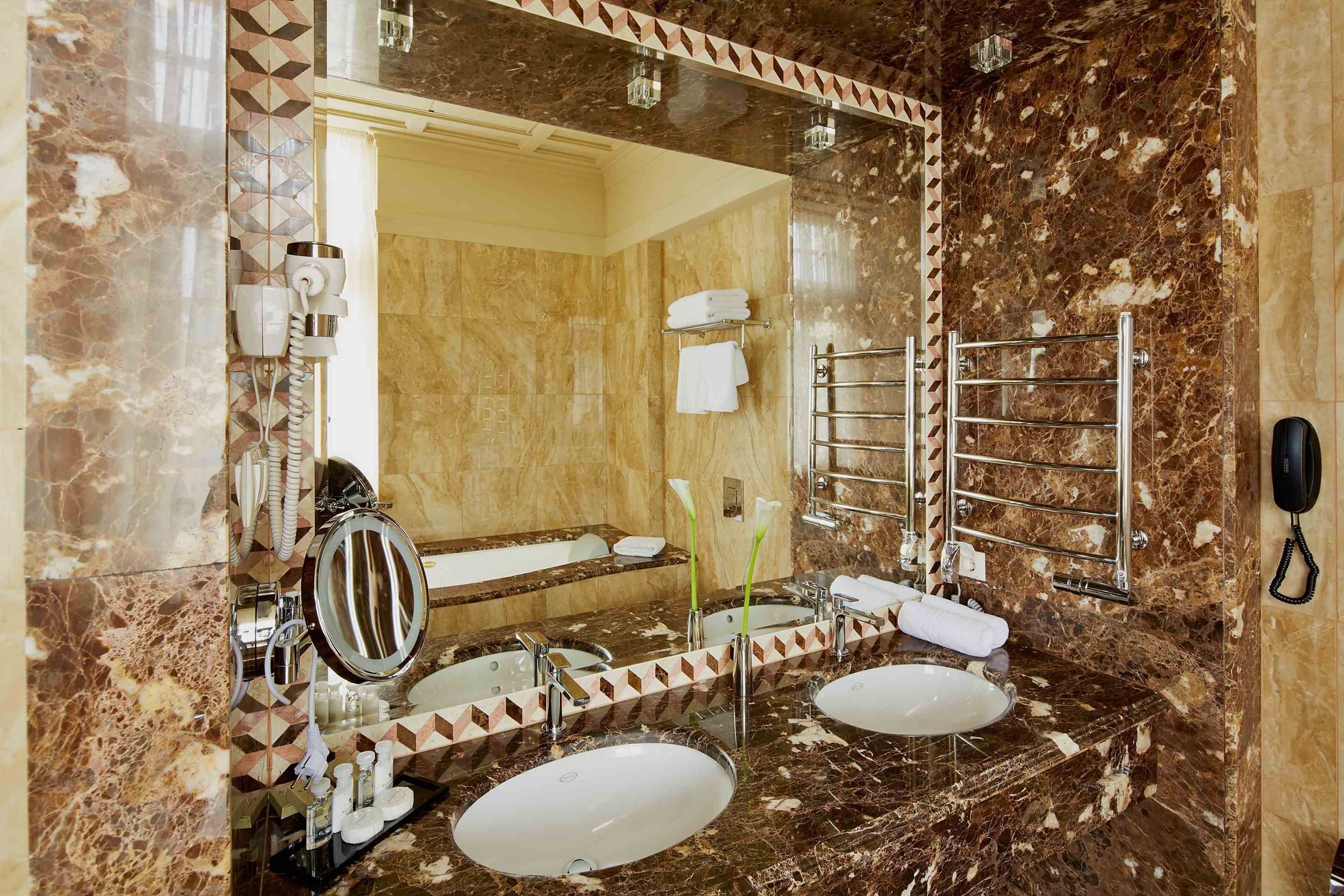 A bathroom with two sinks, a large mirror, a towel rack, and a phone.