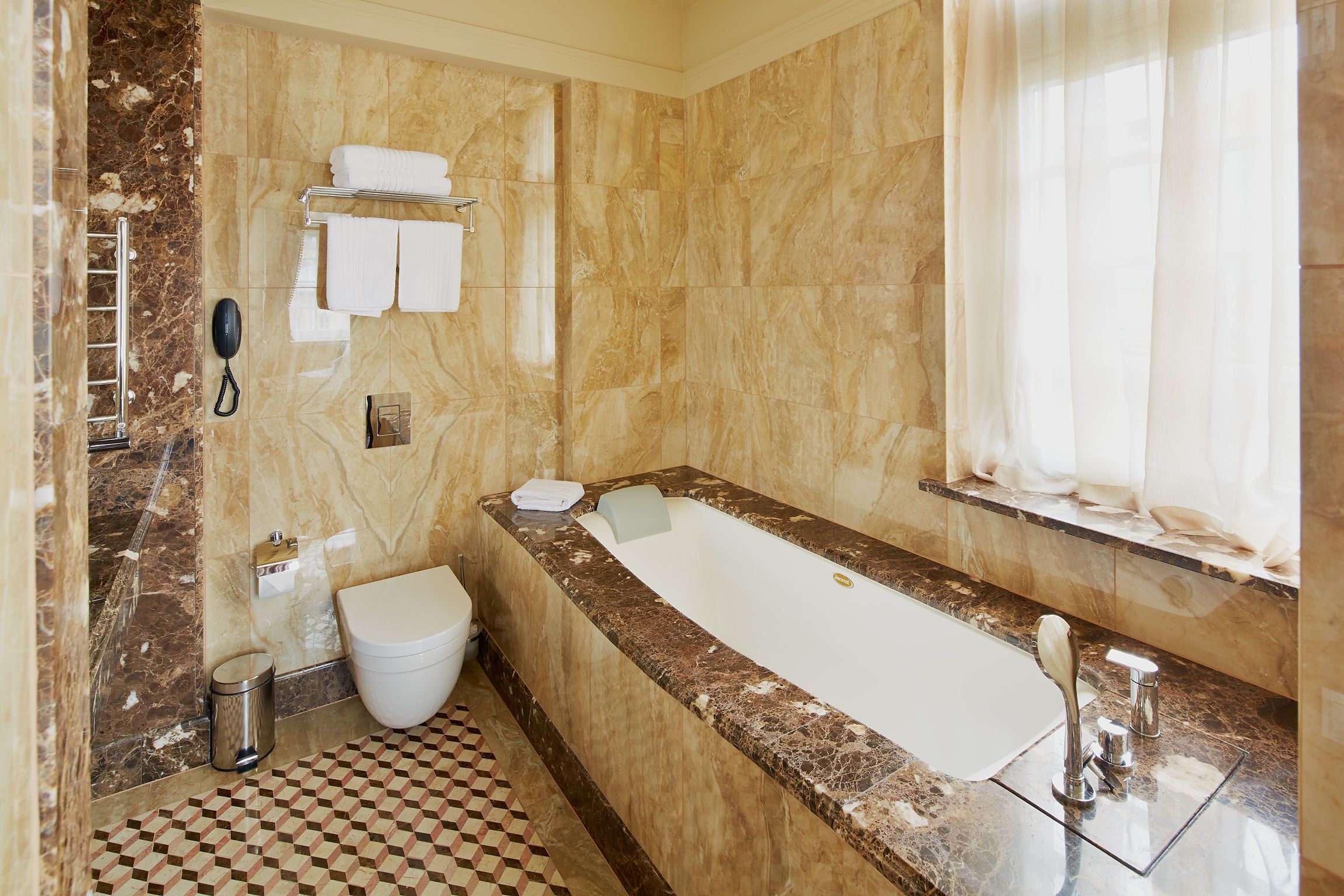 Un baño con piso de mármol, una bañera, un inodoro y un lavamanos.