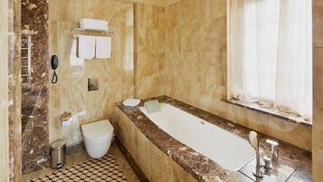 Un baño con piso de mármol, una bañera, un inodoro y un lavamanos.