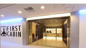 A hotel entrance with a reception desk and a logo for 'First Cabin'. - First Cabin Hakata (Fukuoka)