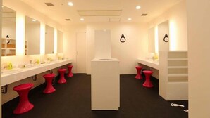 A modern bathroom with white fixtures, multiple sinks, and red stools. - First Cabin Hakata (Fukuoka)