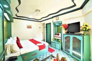 Una habitación de hotel con una cama, un televisor sobre un mueble y un espejo.