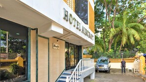 A hotel entrance with a staircase leading to the lobby, a parked vehicle, and a person standing near the entrance. - Hotel Aircraft International (Mumbai)