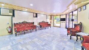 A spacious room with patterned flooring, a fire extinguisher, and two red sofas with intricate designs. - Hotel Aircraft International (Mumbai)