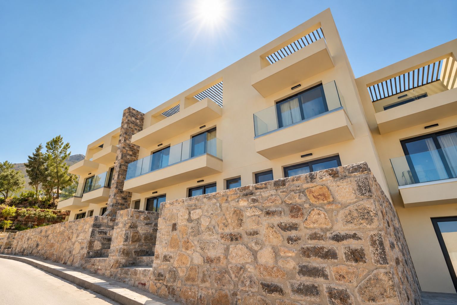 A multi-story hotel with balconies, stone walls, and a clear sky.