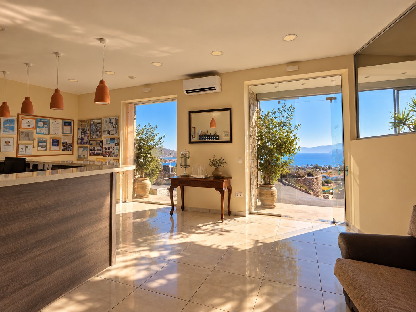 A modern hotel lobby with a reception desk, a dining area, and a view of the sea.