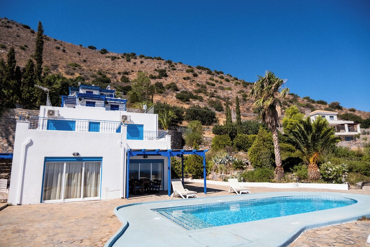 Ein modernes Gebäude mit Pool, Sitzgelegenheiten im Freien und einer Hanglage im Hintergrund.
