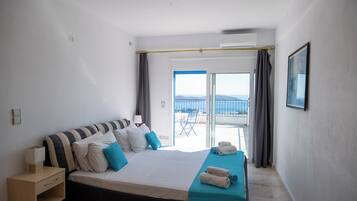 A hotel room with a bed, a nightstand, a window with curtains, and a view of the beach.