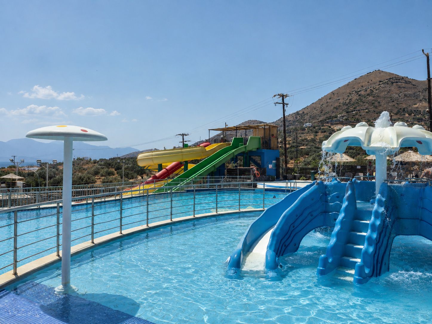 A swimming pool with a water slide and a lifeguard stand.