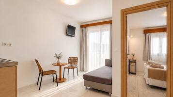 A hotel room with a bed, a small table with chairs, a TV mounted on the wall, and a bathroom visible through an open door.