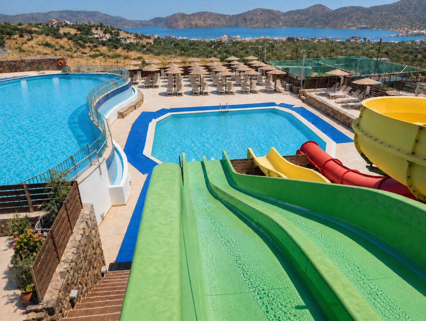 Un espace piscine doté de plusieurs toboggans et de chaises longues.