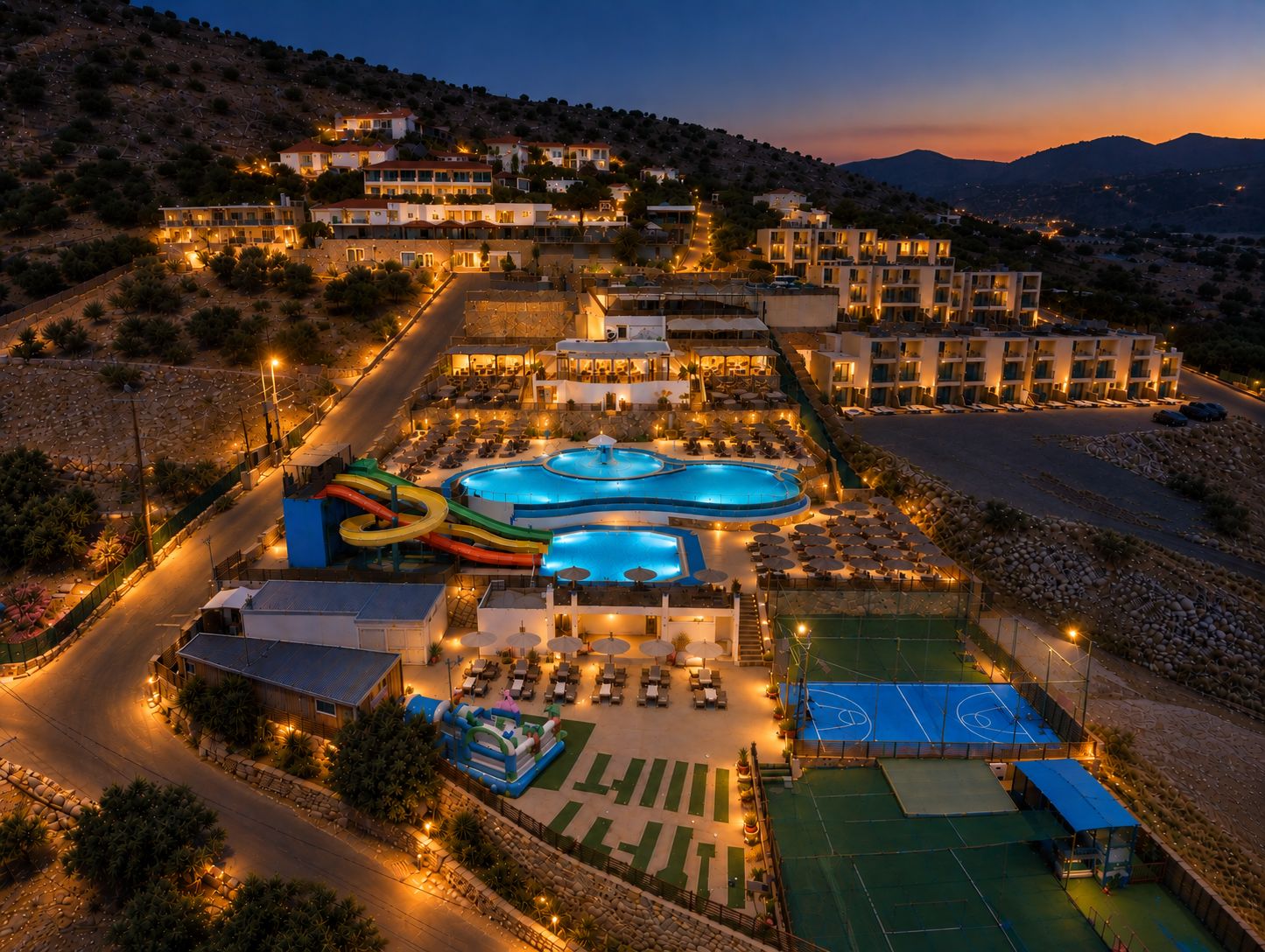 A resort with multiple swimming pools, a water slide, and a tennis court.