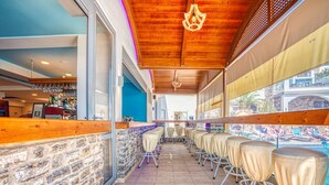 A bar area with a stone wall, wooden ceiling, and a view of the pool.