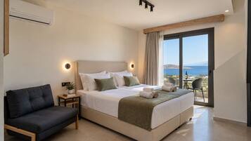 A modern hotel room with a large bed, a sofa, a balcony with a view, and a ceiling-mounted air conditioner.