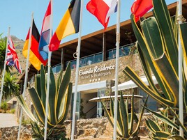Un resort con múltiples banderas, fachada de piedra y un cartel que dice 'Eldunda Residence Resort & Waterpark'.