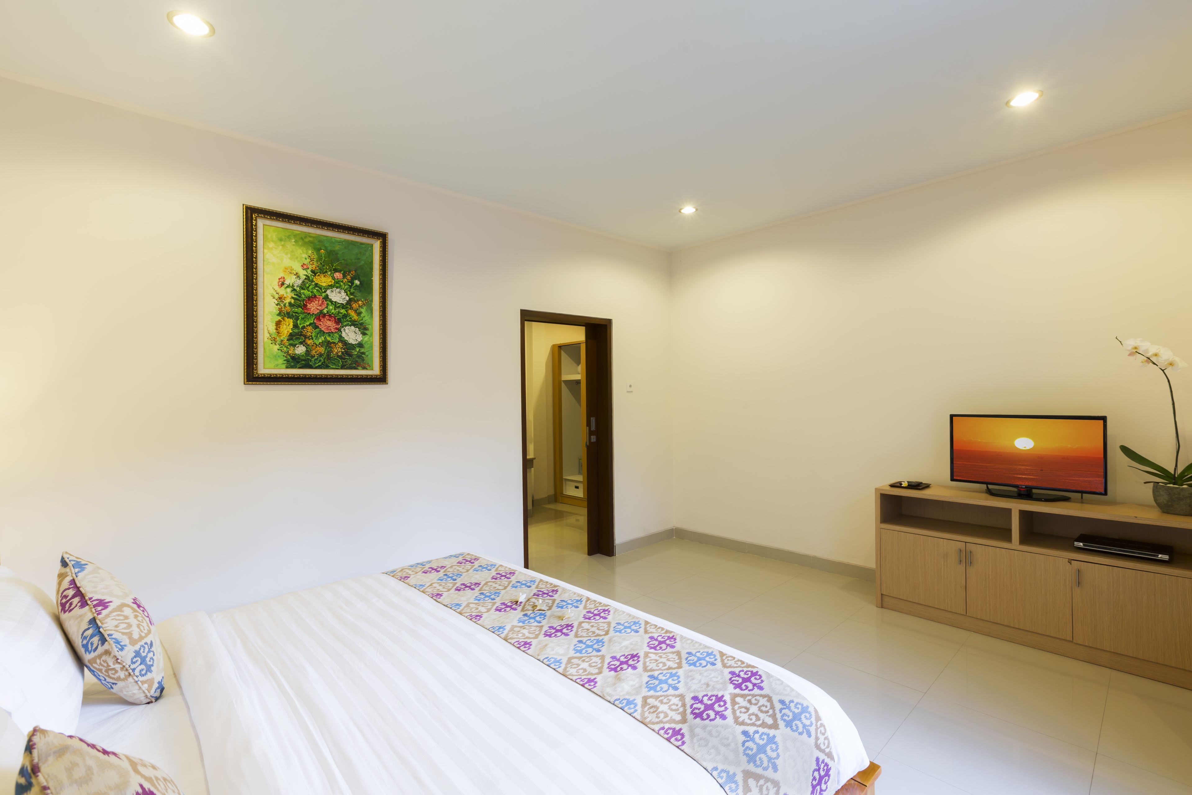 A bedroom with a bed, a television, a cabinet, and a painting on the wall.