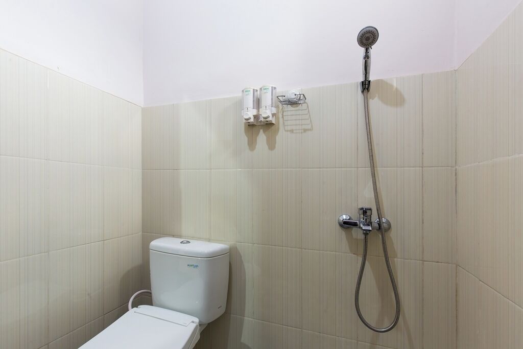 Une petite salle de bain propre, équipée de toilettes, d’une douche et d’un porte-serviettes.