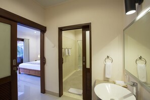 A hotel bathroom with a large mirror, a sink, and a shower area. - Kubal Villa and Living Seminyak (Seminyak)
