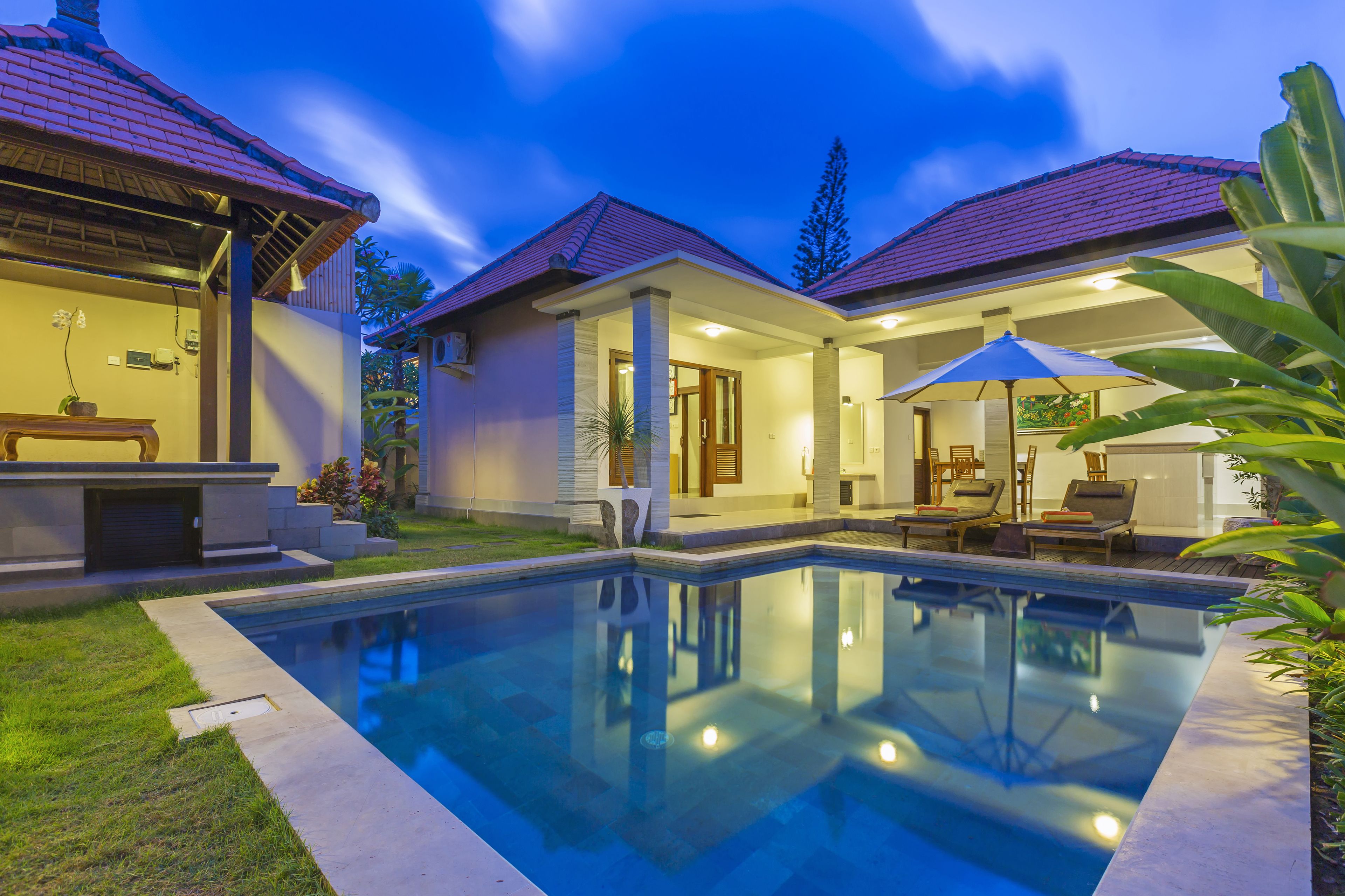 Una propiedad residencial con piscina, terraza cubierta y jardín bien cuidado.